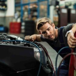 young-auto-mechanic-using-compressor-while-maintaining-ac-unit-car-workshop