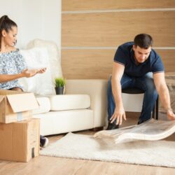 young-smiling-couple-unpacking-cardboard-boxes-together-sitting-sofa-sitting-living-room_482257-24139